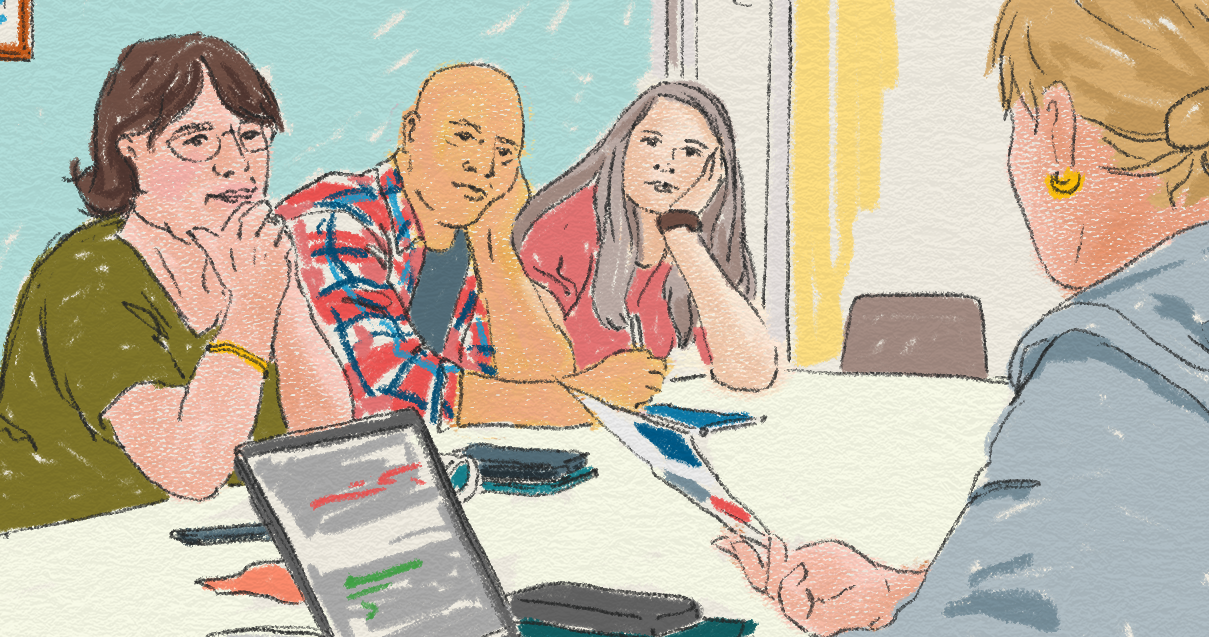 Vuxna personer sitter runt ett bord, en dator är uppslagen