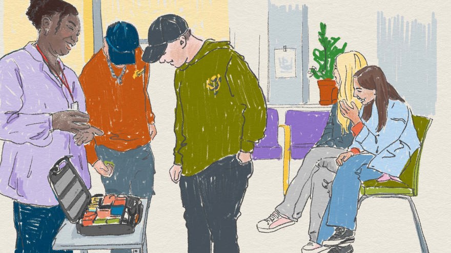 Ett väntrum där ungdomar tittar på något i en väska som en vuxen visar