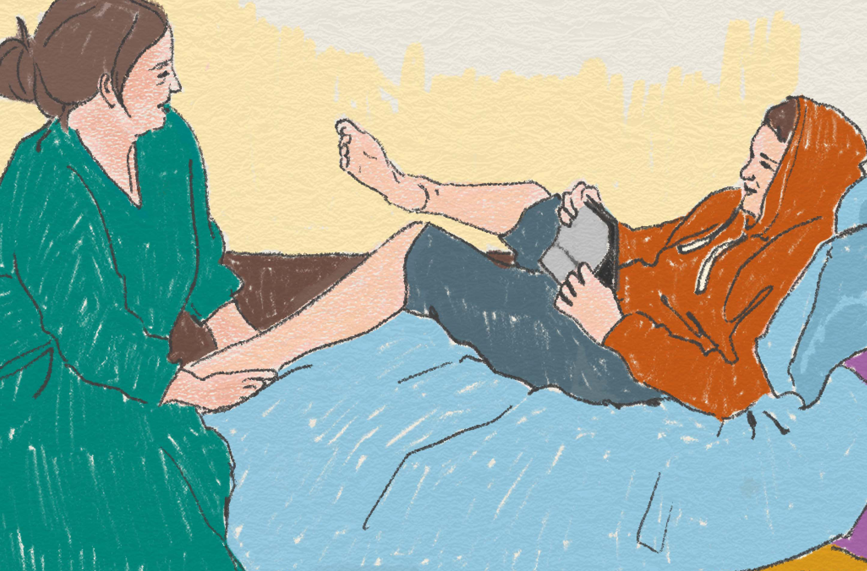 En ungdom ligger i sängen och ser ut att spela något på sin telefon och en vuxen sitter vid fotändan av sängen