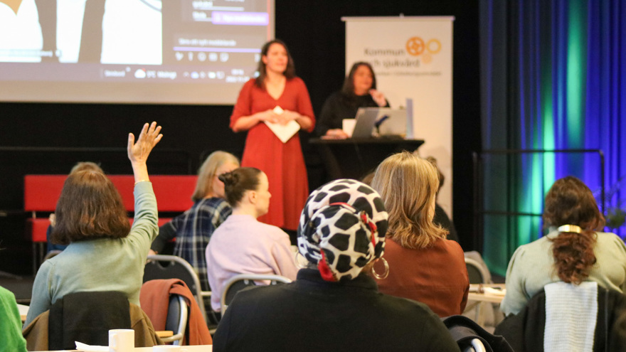 Kvinna räcker upp handen i publiken