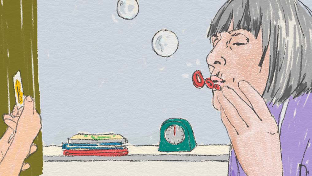 En äldre person blåser såpbubblar inomhus