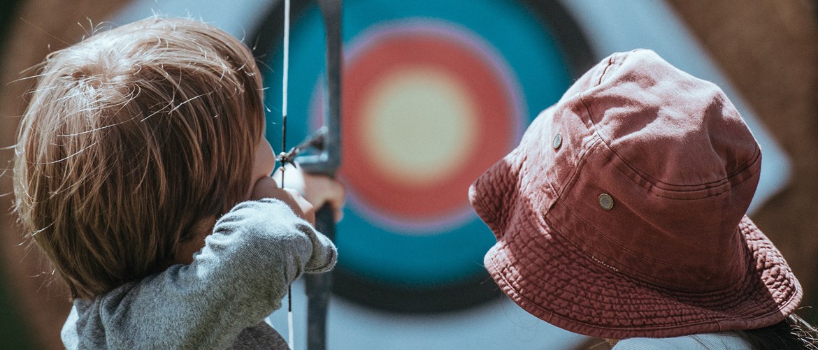 Barn som skjuter pil mot tavla