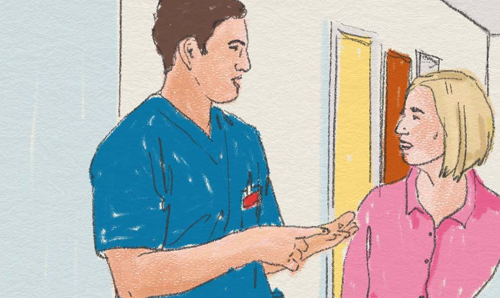 Sjukvårdspersonal pratar med en kvinna i en korridor