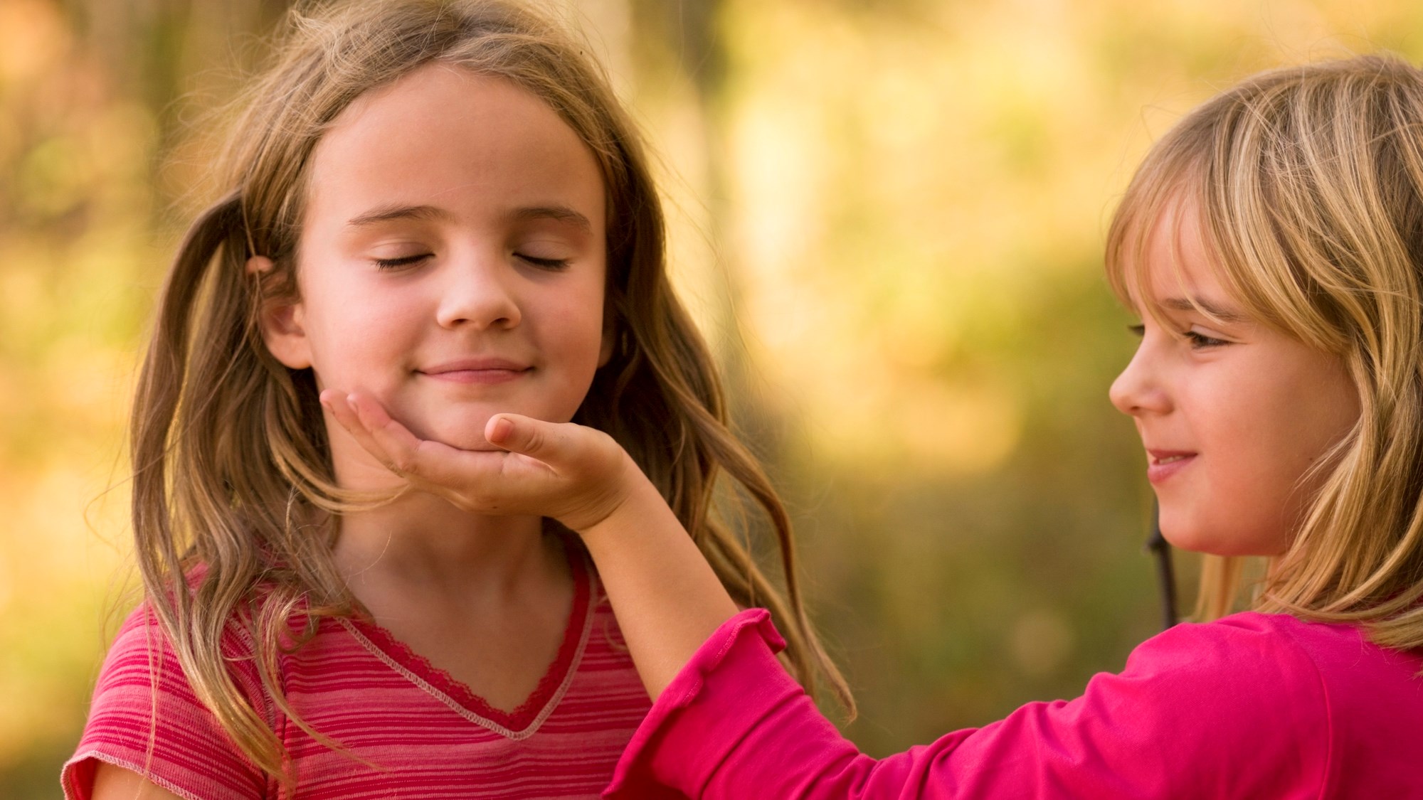 två flickor i röda kläder och blont hår leker